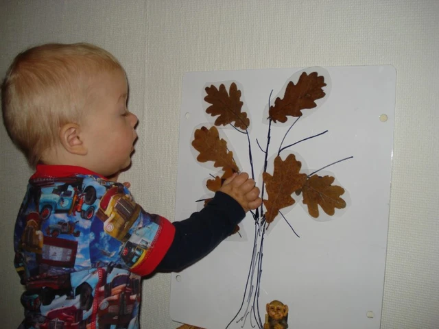 Dreng sætter blade på et malet træ