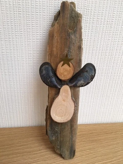 Billede af engel lavet af træskivet og blåmuslinger, sat på et stykke drivtømmer