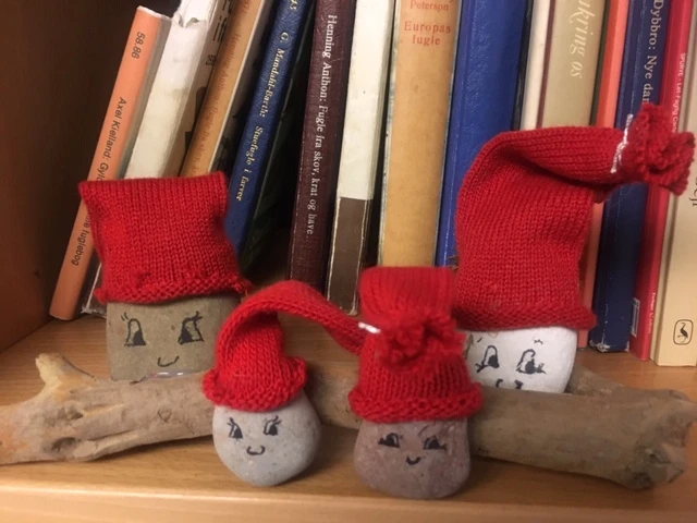 Nisseansigter på sten med røde huer, sidder på et stykke drivtømmer