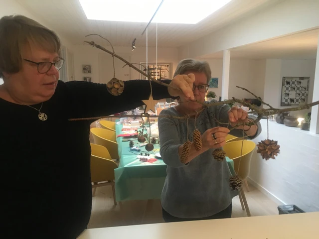 Billede af Anette og Denise der pynter en gren med juleophæng