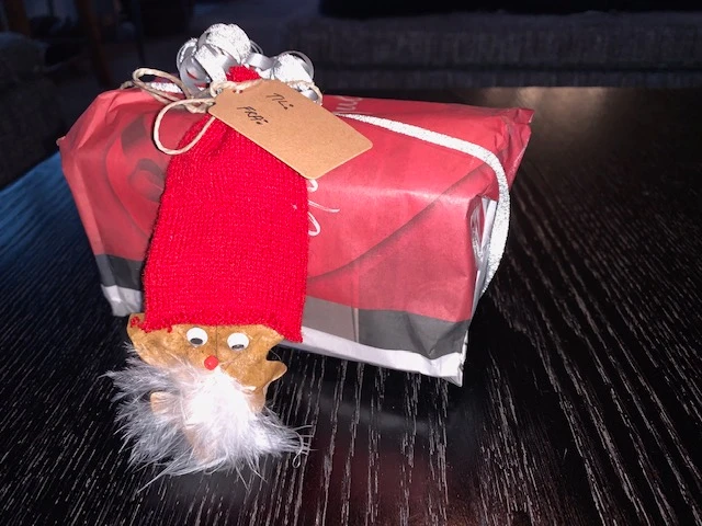 Julegave pakket ind i avispapir, og pyntet med nisse i tubestrik