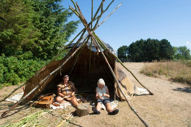 Billede af to der sidder og laver håndarbejde i tipi på Ertebølle stenaldercenter