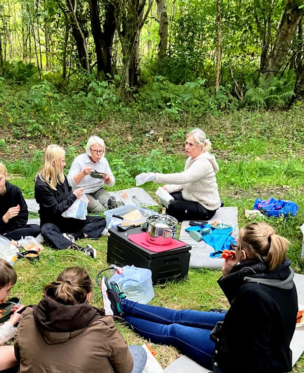 Billede af en gruppe mennesker, der spiser deres mad i skoven