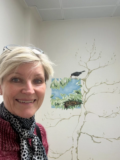 Karin foran et motiv med en solsort og rede